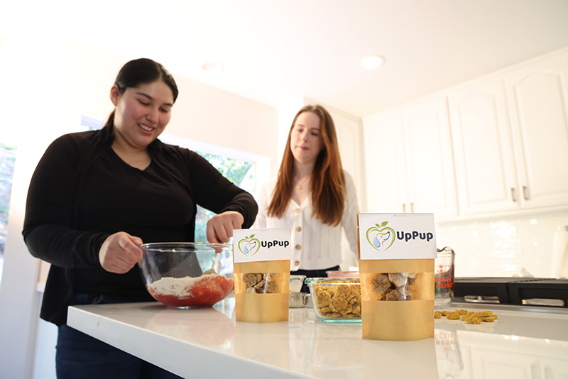 Two cofounders in a kitchen mixing treats